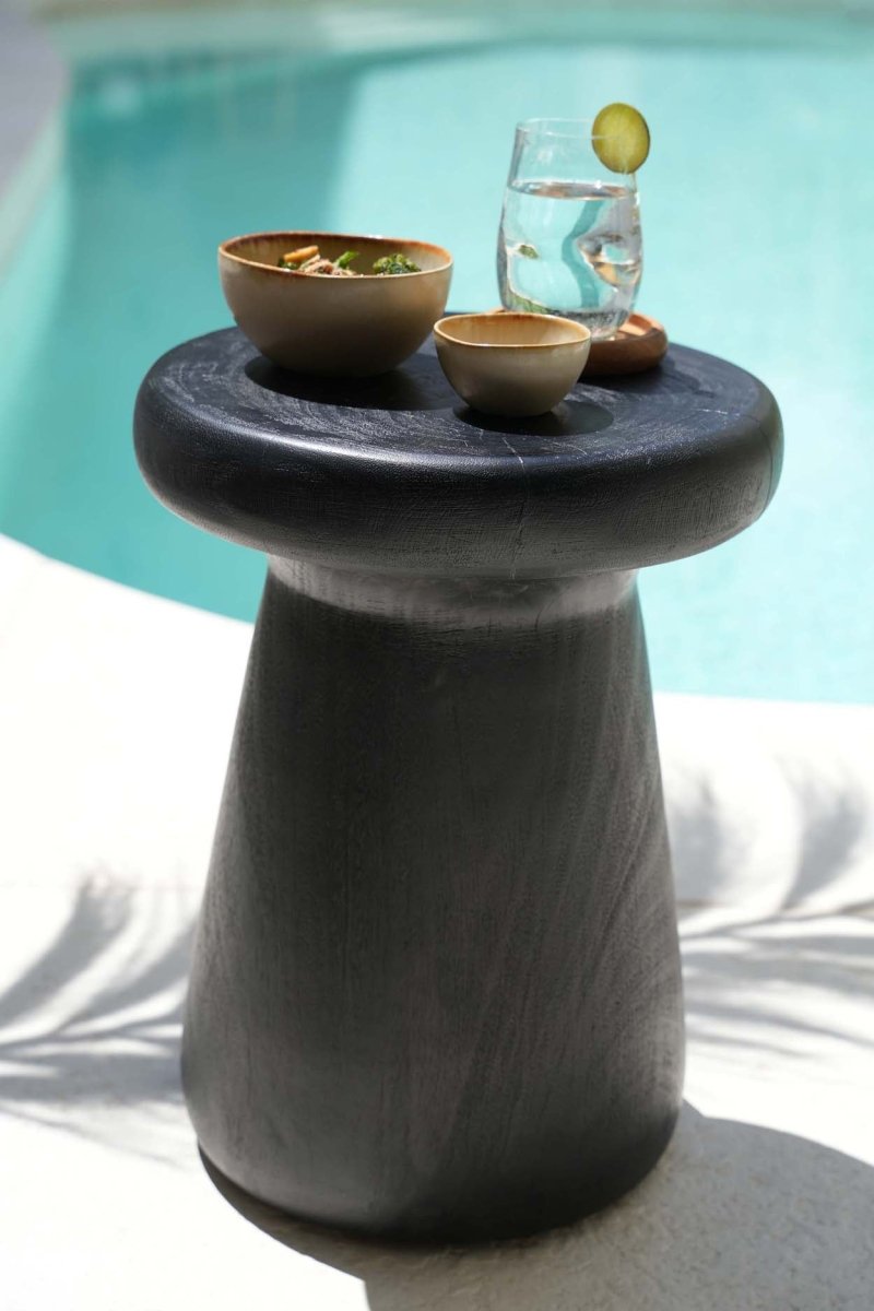 Small stone table with bowls and a glass by a poolside
