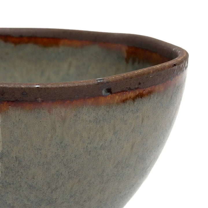 Close-up of a ceramic bowl with a brown rim on a white background
