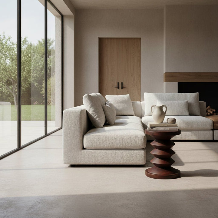 Modern living room with a beige sofa, wooden side table, and large windows.