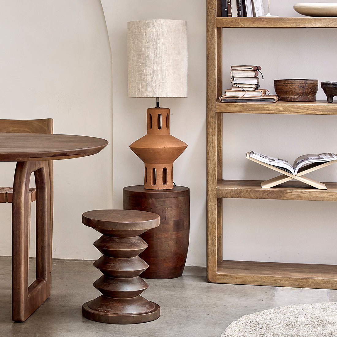 Wooden furniture including a table, stool, and shelf with decorative items in a room setting.