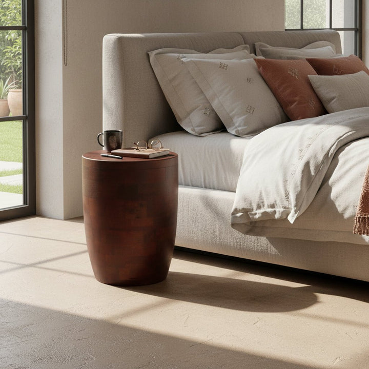 Neatly made bed with pillows and a wooden side table in a bright room.