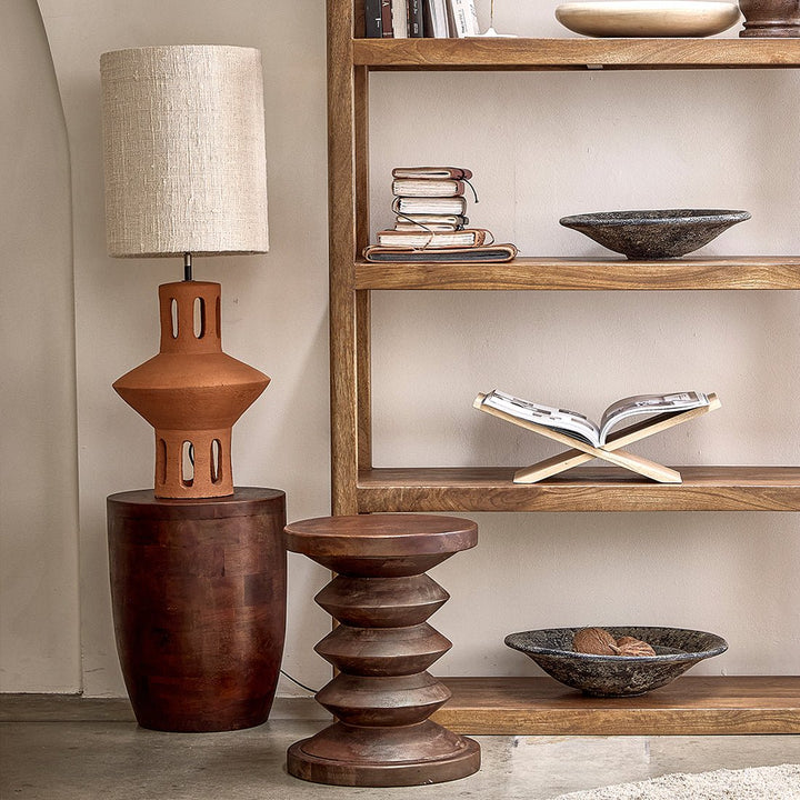 Wooden side table with a lamp and decorative items on a shelf