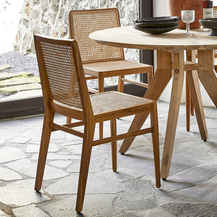 Wooden dining table with two chairs on a stone patio