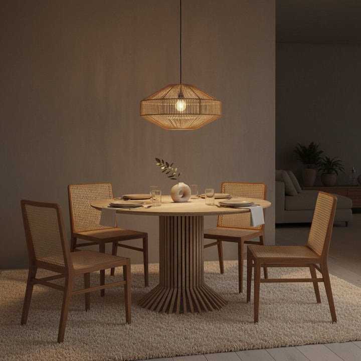 Dining area with a round table and chairs under a pendant light in a dimly lit room.