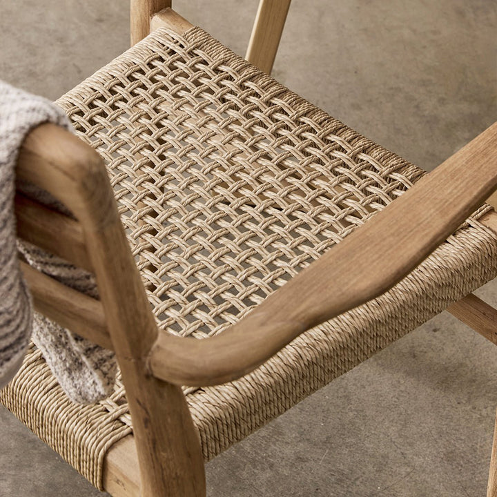 Close-up of a wooden chair with woven seat and backrest on a concrete floor.
