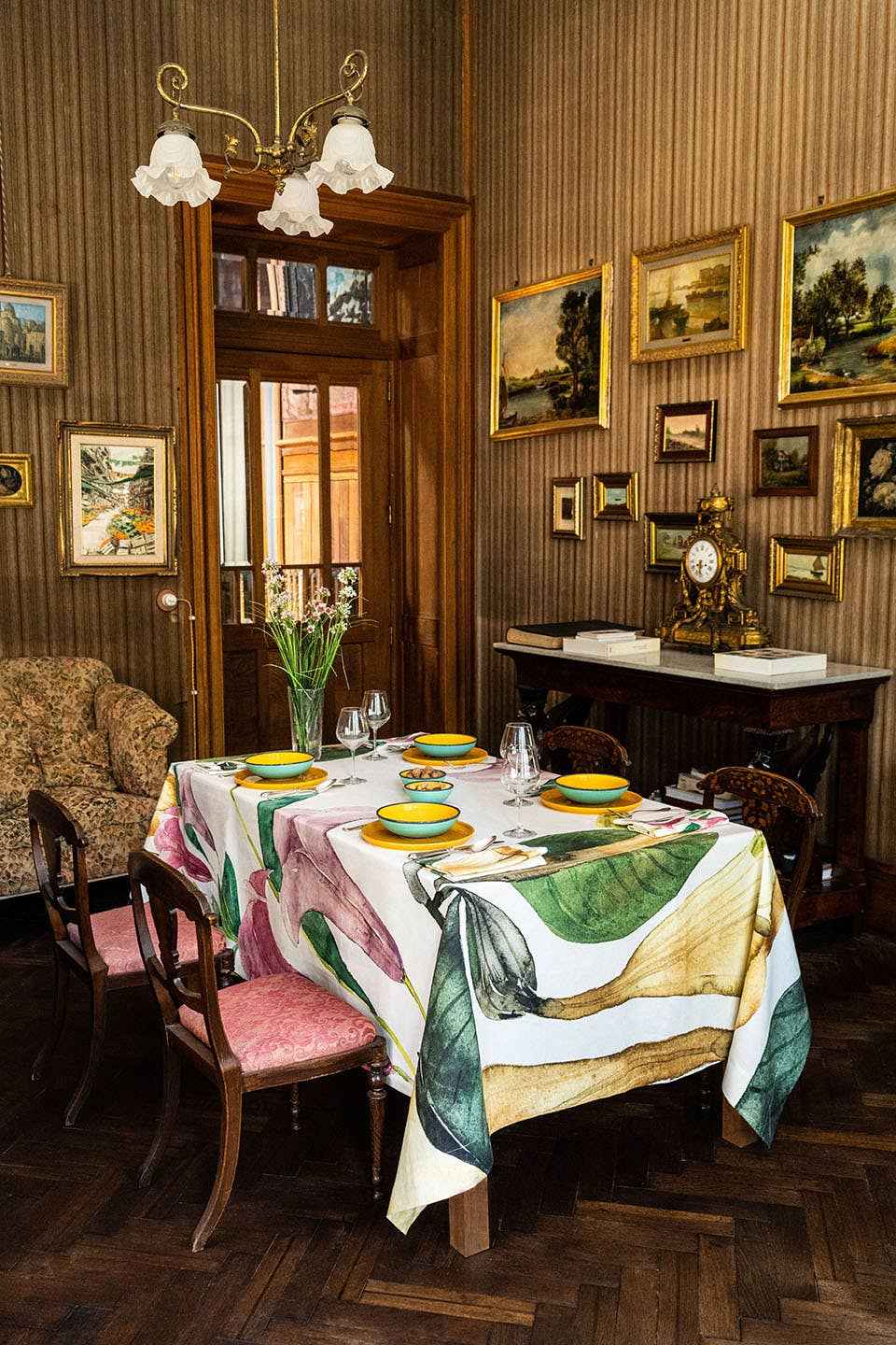 Dining room with a table set for dinner, floral centerpieces, and framed pictures on the wall.