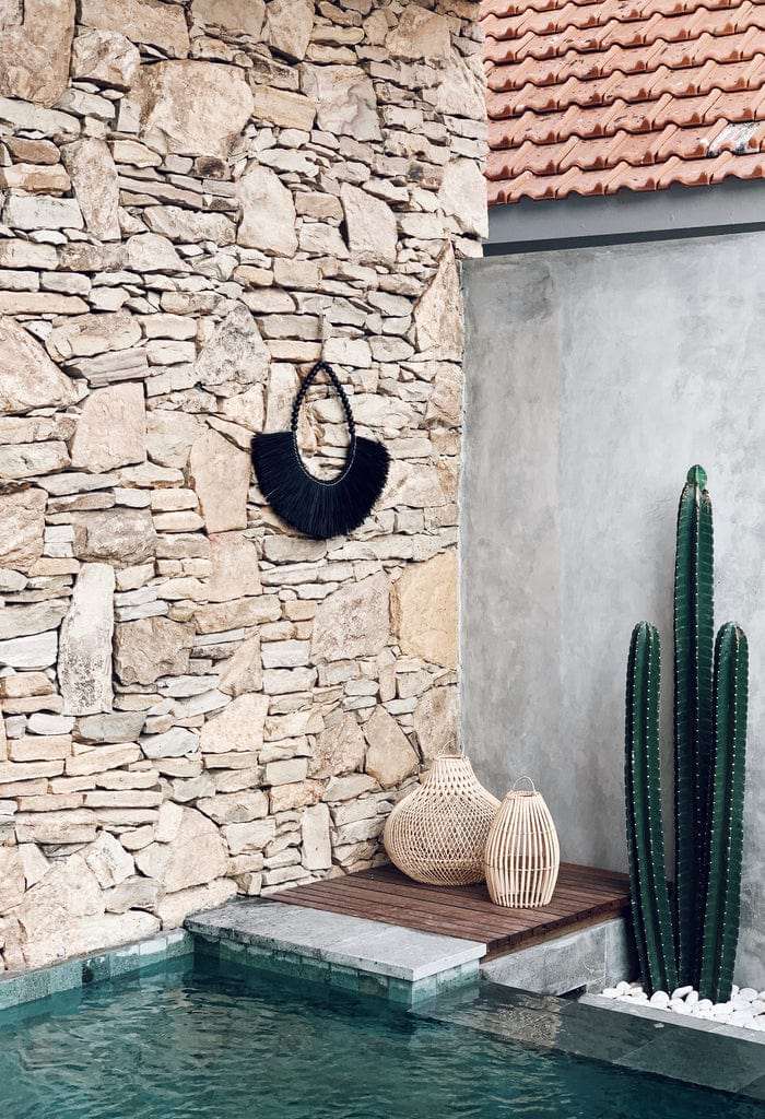 Large Baucau Allang Wall Hanger in black with beads, adding boho-chic style to stone wall decor.