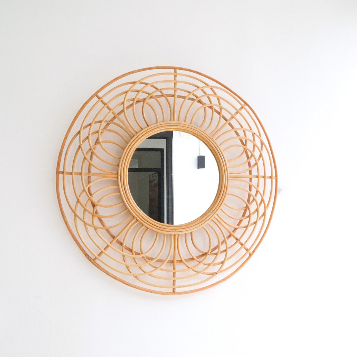 Round rattan wall mirror on a white wall