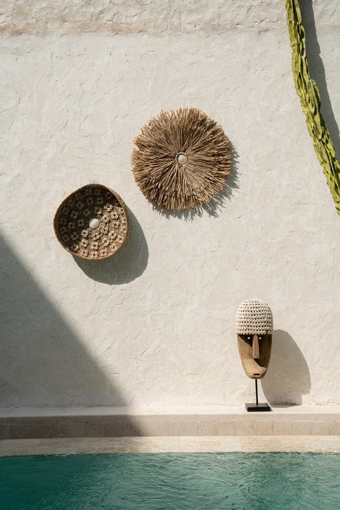 Caribe Shell Plate - Natural White 42cm diam displayed on a textured wall above a pool.