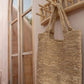 Island Coat Rack made of solid teak wood hanging on a wall, with a natural woven bag hanging from it.