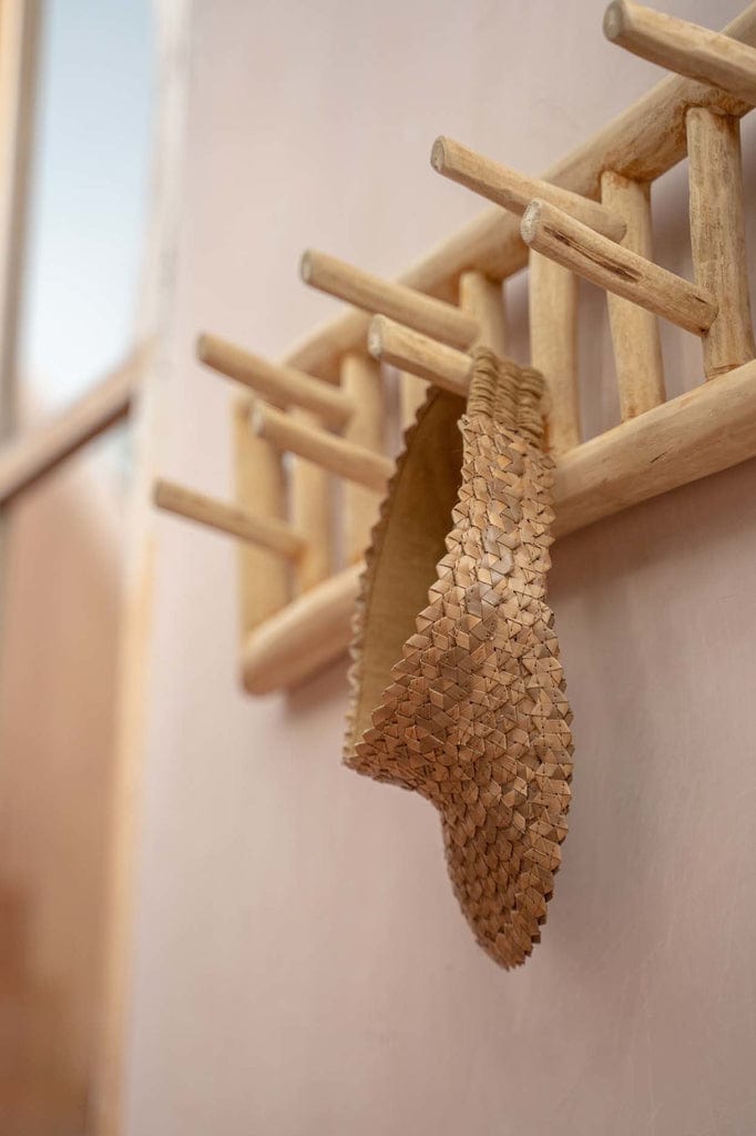 Island Coat Rack in natural teakwood, used indoors for hanging essentials.