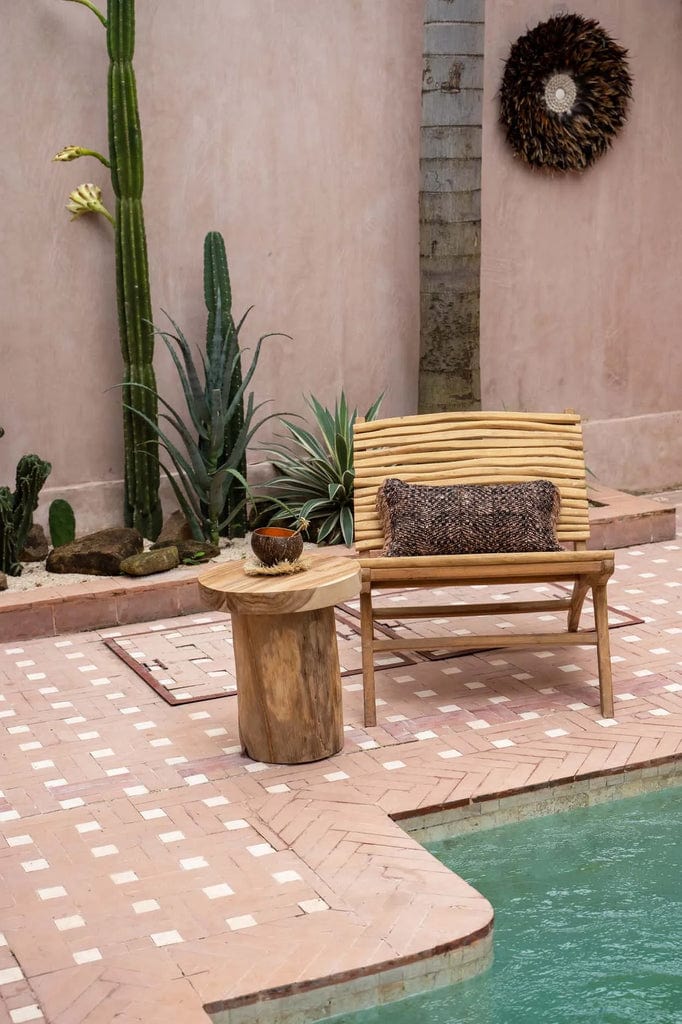 Handcrafted teak wood chair by a pool, showcasing unique design for outdoor comfort.