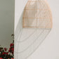 Lalo Wall Lamp - Natural rattan wall sconce on white wall with red flowers.