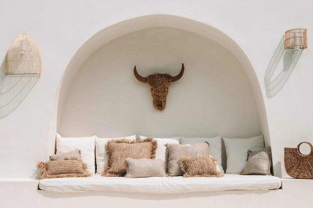 Rustic seating area featuring the natural Lalo Wall Lamp made of rattan, complementing the cozy ambiance.