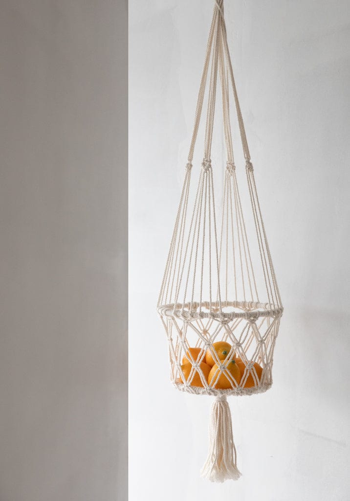 Macrame Planthanger in white with a bohemian design, displaying oranges indoors.