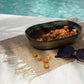 Comporta Oval Bowl 25cm with snacks by a poolside on a woven mat.