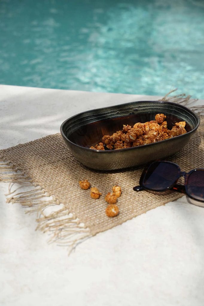 Comporta Oval Bowl 25cm with snacks by a poolside on a woven mat.