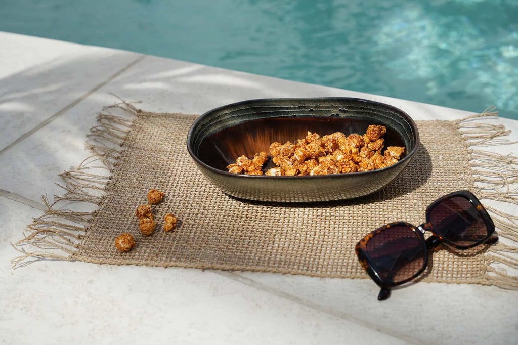 Comporta Oval Bowl 25cm displayed by a pool with sunglasses and snacks.