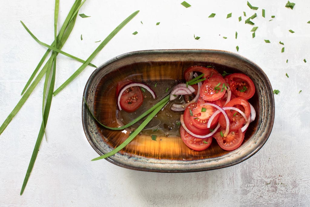 Comporta Oval Bowl 25cm with salad, showcasing unique color variations and crackle glaze.