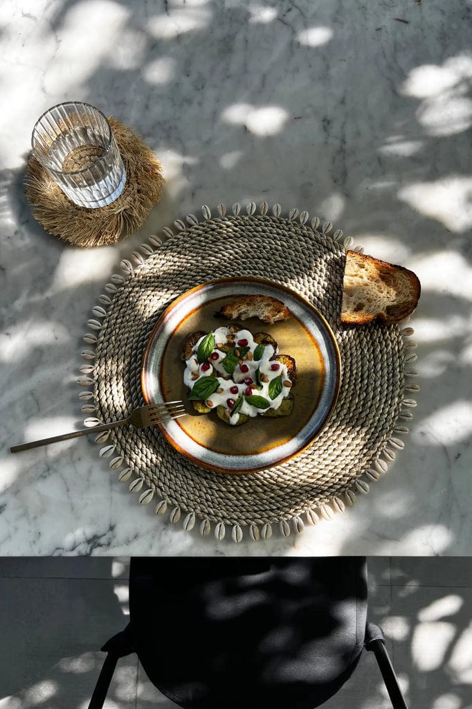 Seagrass Shell Placemat with cowrie border on a dining table.