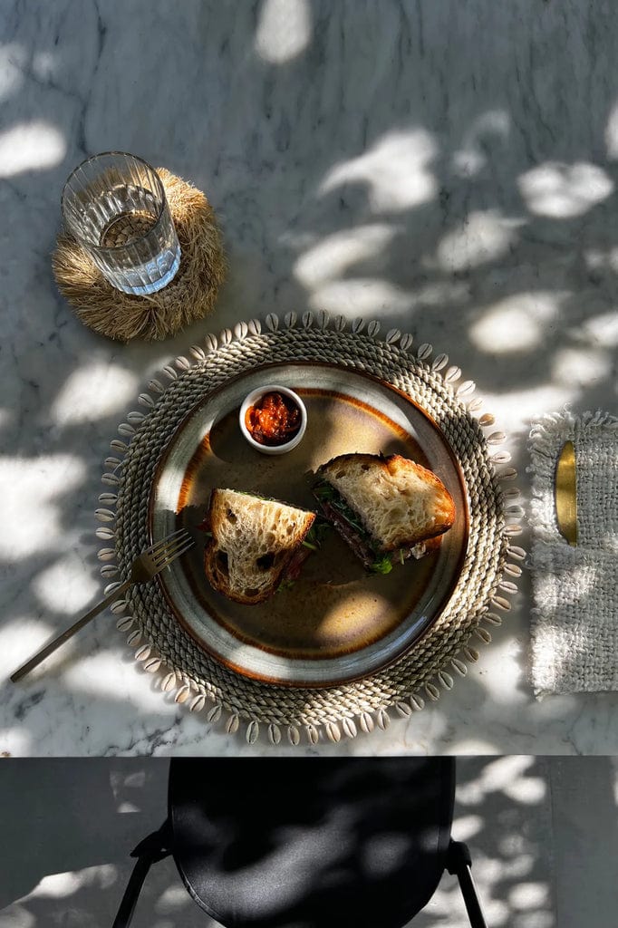 Seagrass Shell Placemat with cowrie shell border on dining table.