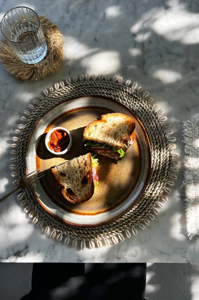 Seagrass Shell Placemat with cowrie shell border under a sandwich and dip.