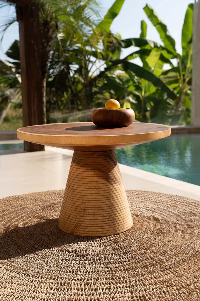 Seagrass rug in natural hue, 100cm round, under a wooden table by a pool.