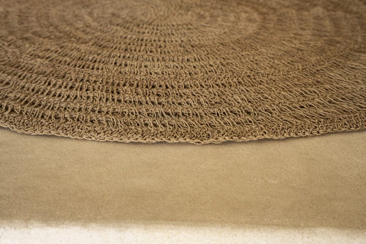 Circular seagrass rug natural 100cm, handcrafted from raffia, sisal, and palm, enhancing home decor with warmth and durability.