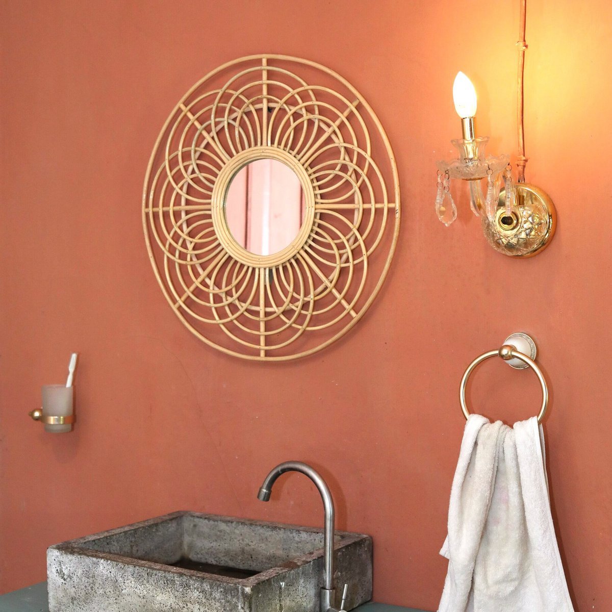 Decorative wall mirror with geometric design on a peach-colored wall, next to a sink and towel.