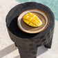 Comporta Dessert Plate with sliced mango on textured black table near pool.