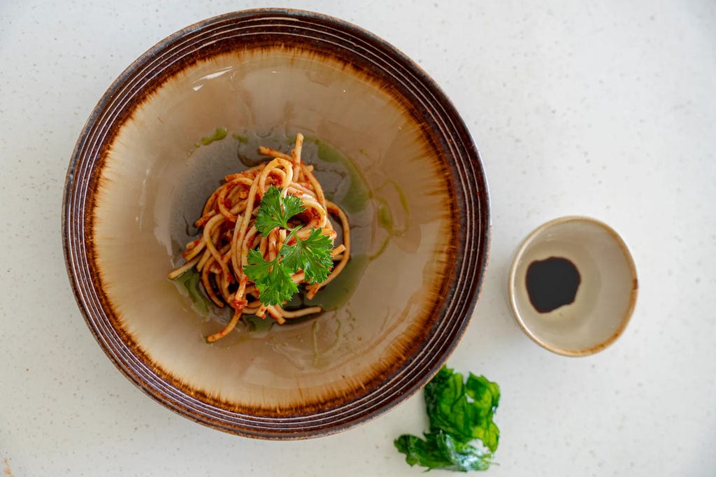 Comporta Pasta Plate 22cm with Crackle Glaze featuring a dish of spaghetti.