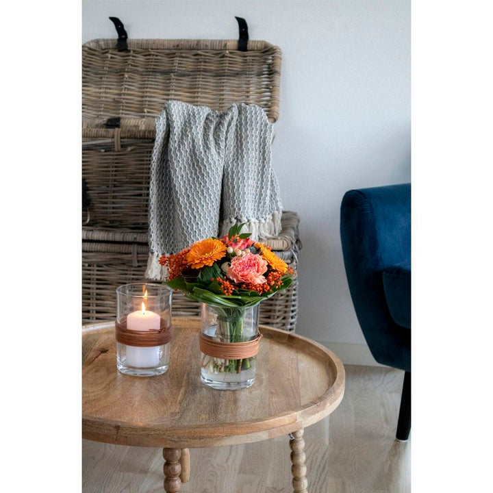 Natural mango wood coffee table round Ø60x35 cm with candle and flowers in modern living room.