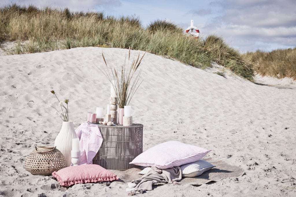 Eliana Marble Candle Holder on sandy beach setup with pillows and decor.