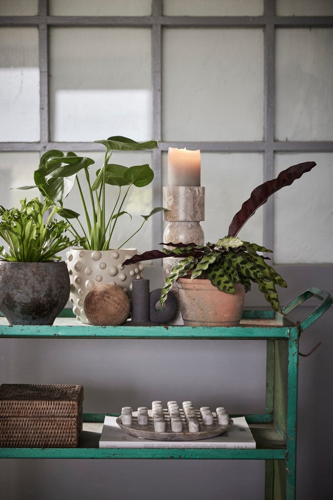 Ellia Solitaire Game marble board on a decorative shelf, surrounded by plants.