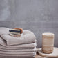Travina tray Ø19.5 cm in linen on wooden surface with folded towels and grooming items.