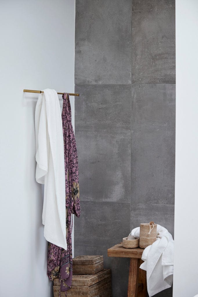 Travina Linen Jar in a modern bathroom setting with towels, showcasing a 16.5x10.5 cm exquisite travertine design.