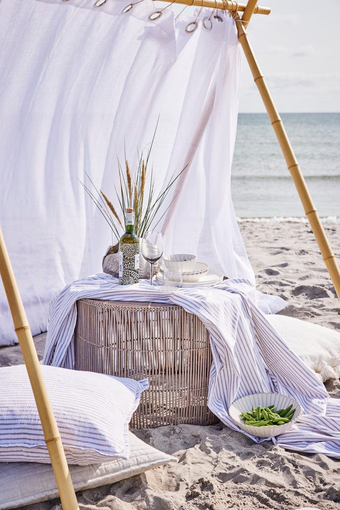 Olivia Tablecloth Ø140 cm with sand striped pattern on a table by the beach.