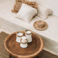 Pretty candle holder in white terracotta with raffia accent on a wooden table.