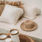 White terracotta candle holders with raffia accents displayed on a wooden surface.