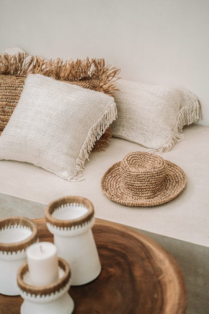 White terracotta candle holders with raffia accents displayed on a wooden surface.