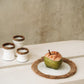 Pretty Candle Holder in white terracotta with raffia accents on a table.