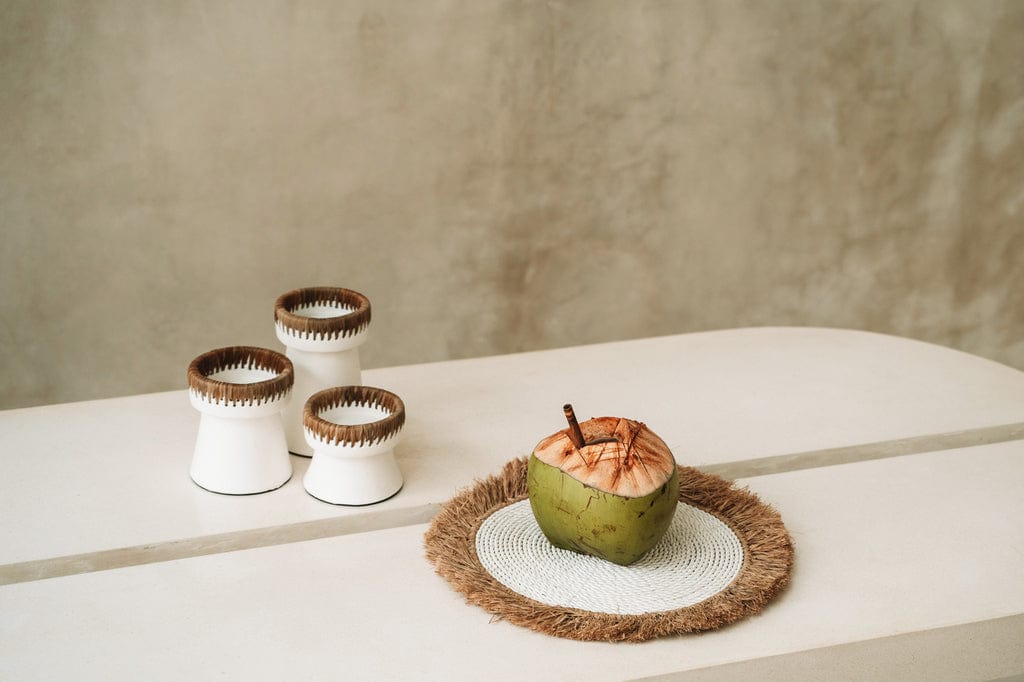 Pretty Candle Holder in white terracotta with raffia accents on a table.